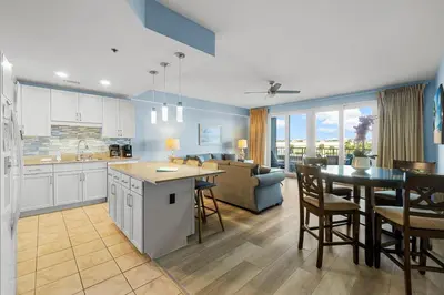 a kitchen and living room with a table and a couch at Lovely Resort Low Floor Condo! Just Steps to the Beach & Restaurants! by Dolce Vita Getaways PCB in Panama City Beach
