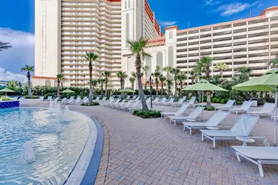 a pool with white lounge chairs and a hotel at Lovely Resort Low Floor Condo! Just Steps to the Beach & Restaurants! by Dolce Vita Getaways PCB in Panama City Beach