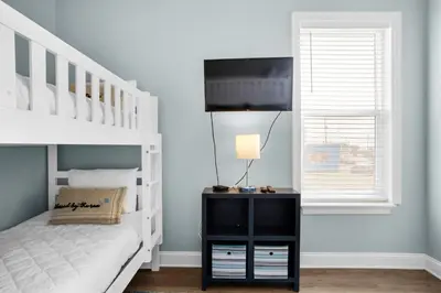 a bedroom with a white bunk bed and a television at Vista del Mar I BEST Day 202 in Panama City Beach