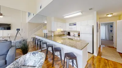 a kitchen and living room with a counter and chairs at Southwind Condominiums 6-B in Panama City Beach