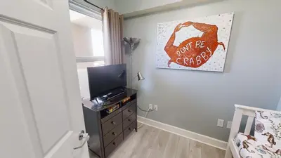 a bedroom with a tv and a dresser with a picture at Sunrise Beach 1408 in Panama City Beach