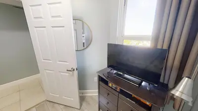 a living room with a flat screen tv next to a door at Sunrise Beach 1408 in Panama City Beach