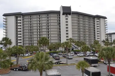 a large white building with palm trees in a parking lot at Gulf front condo in Panama City Beach