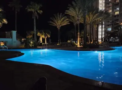 a large swimming pool with palm trees at night at Shores of Panama 2003 - Renovated 2 bedroom, with Bunkroom Sleeps 6 with a Reserved Parking Space! condo in Panama City Beach