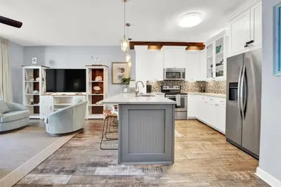 a kitchen with white cabinets and a sink and a refrigerator at Spring Break Friendly Ages 21–25+ OK in Panama City Beach