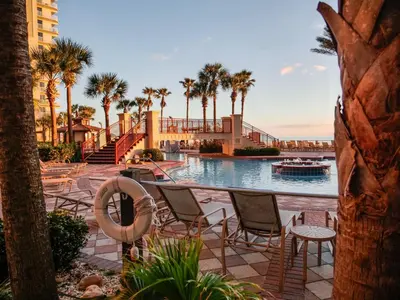 a pool at a resort with chairs and palm trees at Spring Break Friendly Ages 21–25+ OK in Panama City Beach