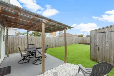 a patio with a table and chairs and a fence at Blue Neptune at 5313 Sunset Avenue by Nautical Properties Vacation Rentals in Panama City Beach