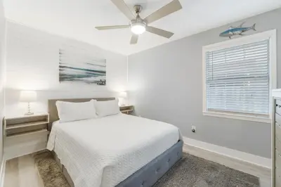 a white bedroom with a bed and a ceiling fan at Blue Neptune at 5313 Sunset Avenue by Nautical Properties Vacation Rentals in Panama City Beach