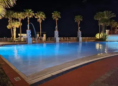 a large swimming pool with palm trees at night at Shores of Panama 1206 - Amazing Studio, Free Fun! Sleeps 3, Romantic condo in Panama City Beach