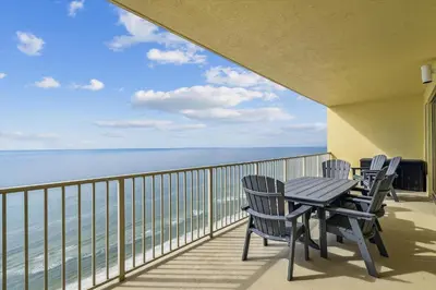 a balcony with chairs and a table and the ocean at Gulf Crest 2005 - 2 Bedroom 2Bathroom withFantastic View! Family Friendly! Sleeps 8 condo in Panama City Beach
