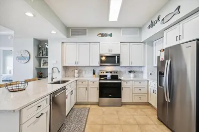 a kitchen with white cabinets and a stainless steel refrigerator at Gulf Crest 2005 - 2 Bedroom 2Bathroom withFantastic View! Family Friendly! Sleeps 8 condo in Panama City Beach