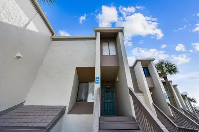 a white building with a green door and stairs at Sugar Beach A6-Lovely 4 bedroom 3 bath Condo, Sleeps 11, Free Beach Chairs 2021! condo in Panama City Beach