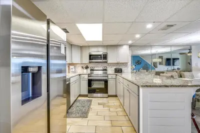 a kitchen with white cabinets and granite counter tops at Sugar Beach A6-Lovely 4 bedroom 3 bath Condo, Sleeps 11, Free Beach Chairs 2021! condo in Panama City Beach