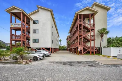a couple of buildings with cars parked in a parking lot at Cozy Holiday Hideaway, Sleeps 4! Steps to the Beach! Renovated 2021 condo in Panama City Beach