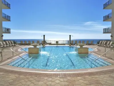 a swimming pool with chairs and the ocean in the background at Origin 1036, Perfect for 4! Beautiful sunset and Gulf of Mexico view! Free Activities! condo in Panama City Beach