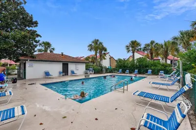 a swimming pool with blue chairs and people in it at Edgewater Villas #2108 - 2 Bedroom 2Bath Sleeps 8, Free Gas Card & Free Fun! condo in Panama City Beach