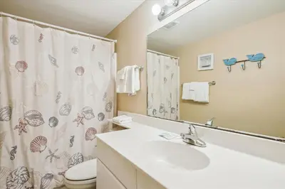 a bathroom with a sink and a toilet and a shower curtain at Shores of Panama 1506, Perfect for a Great Couples Getaway! Free Fun! Reserved Parking condo in Panama City Beach