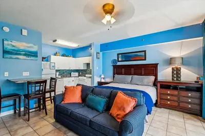 a bedroom with a bed and a couch and a kitchen at Shores of Panama 1506, Perfect for a Great Couples Getaway! Free Fun! Reserved Parking condo in Panama City Beach