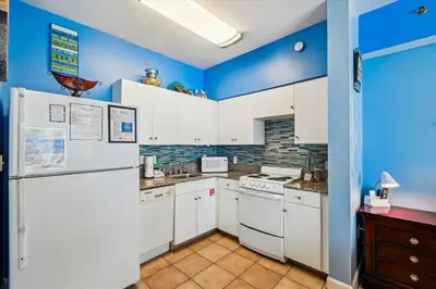 a kitchen with white appliances and blue walls at Shores of Panama 1506, Perfect for a Great Couples Getaway! Free Fun! Reserved Parking condo in Panama City Beach