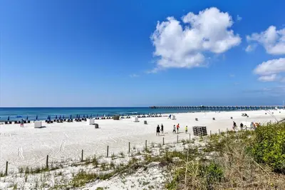 a beach with a group of people and a pier at Sterling Reef 202 - 2nd Floor withUninterrupted Gulf View! Free Fun! Free Gas Card! condo in Panama City Beach
