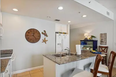a kitchen with a sink and a clock on the wall at Sterling Reef 202 - 2nd Floor withUninterrupted Gulf View! Free Fun! Free Gas Card! condo in Panama City Beach