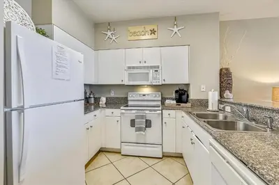 a white kitchen with a sink and a stove at Shores of Panama 620-Sleeps 8, Free Fun! Reserved Parking Space! Updated! condo in Panama City Beach