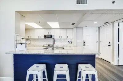 a large kitchen with three stools at a counter at Long Beach Tower 3, #1303 - Completely Renovated 2 Bedroom Sleeps 8, condo in Panama City Beach