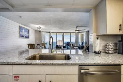 a kitchen with a sink and a living room at Long Beach Tower 3, #1303 - Completely Renovated 2 Bedroom Sleeps 8, condo in Panama City Beach