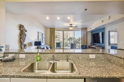 a kitchen with a sink and a living room at Shores of Panama 316 - 3rd Floor 1 Bedroom, Sleeps 6, Reserved Parking Space, Free Daily Fun! condo in Panama City Beach
