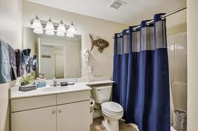 a bathroom with a toilet and a blue shower curtain at Shores of Panama 316 - 3rd Floor 1 Bedroom, Sleeps 6, Reserved Parking Space, Free Daily Fun! condo in Panama City Beach