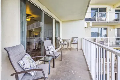 a balcony with chairs and tables and windows at Shores of Panama 316 - 3rd Floor 1 Bedroom, Sleeps 6, Reserved Parking Space, Free Daily Fun! condo in Panama City Beach