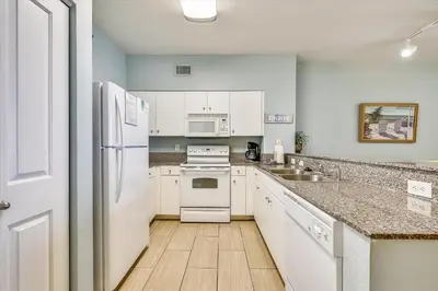a kitchen with white appliances and a wooden floor at Shores of Panama 821-2 Bd 3Ba, Sleeps 8! Updated, No Carpet! Free Fun! condo in Panama City Beach