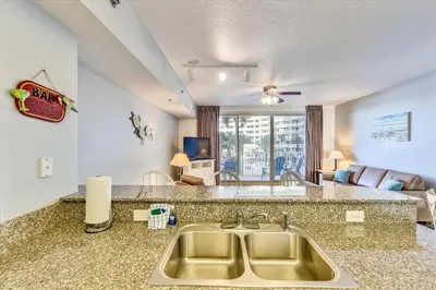a kitchen with a sink and a living room at Shores of Panama 325 - 3rd Floor, Updated, Free Fun! Sleeps 6, condo in Panama City Beach