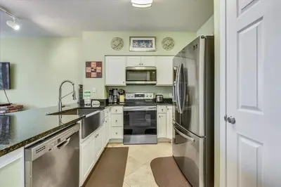 a kitchen with white cabinets and a stainless steel refrigerator at Shores of Panama 204 - 2nd Floor 2 Bedroom Sleeps 8, Same Floor Reserved Parking, Free Fun condo in Panama City Beach