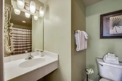 a bathroom with a sink and a toilet and a mirror at Shores of Panama 204 - 2nd Floor 2 Bedroom Sleeps 8, Same Floor Reserved Parking, Free Fun condo in Panama City Beach