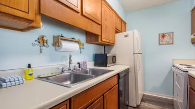 a kitchen with a sink and a refrigerator at Endless Summer #C4 by Nautical Properties Vacation Rentals in Panama City Beach