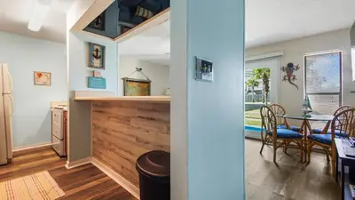 a kitchen and dining room with a wooden wall at Endless Summer #C4 by Nautical Properties Vacation Rentals in Panama City Beach