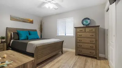 a bedroom with a bed with blue pillows and a dresser at Compass Cove at Gulf Highlands by Nautical Properties Vacation Rentals in Panama City Beach
