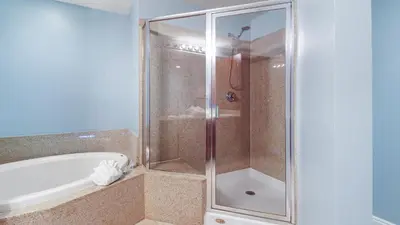 a shower with a glass door next to a bath tub at Laketown Wharf #101 by Nautical Properties Vacation Rentals in Panama City Beach