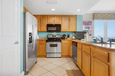 a kitchen with wooden cabinets and stainless steel appliances at Grandview East 301 in Panama City Beach
