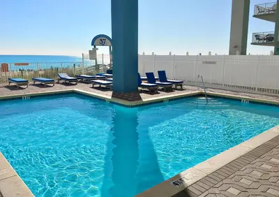 a large swimming pool with chairs and the ocean at Grandview East 301 in Panama City Beach