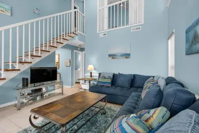 a living room with a blue couch and a table at Horizon South 51B in Panama City Beach