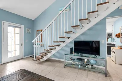 a living room with a staircase with a flat screen tv at Horizon South 51B in Panama City Beach