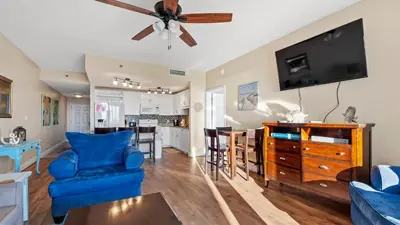 a living room with a blue couch and a ceiling fan at Laketown Wharf #1211 by Nautical Properties Vacation Rentals in Panama City Beach