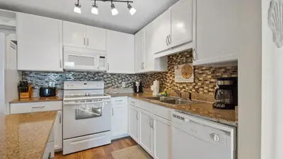 a white kitchen with white cabinets and a sink at Laketown Wharf #1211 by Nautical Properties Vacation Rentals in Panama City Beach