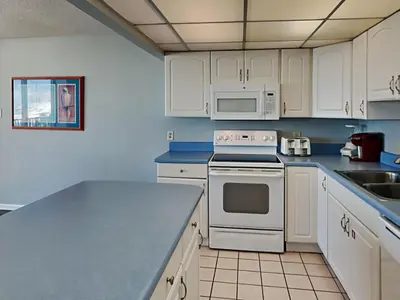 a kitchen with white cabinets and a counter top at Edgewater Leeward #206 in Panama City Beach