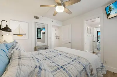 a white bedroom with a bed and a ceiling fan at Sunbird Resort! Direct Beachfront Condo! Free Beach Chairs! by Dolce Vita Getaways PCB in Panama City Beach