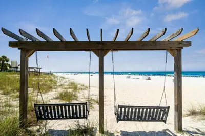 two benches sitting in a swing on the beach at Sunbird Resort! Direct Beachfront Condo! Free Beach Chairs! by Dolce Vita Getaways PCB in Panama City Beach