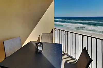 a table on a balcony with a view of the ocean at Grandview East #703 in Panama City Beach