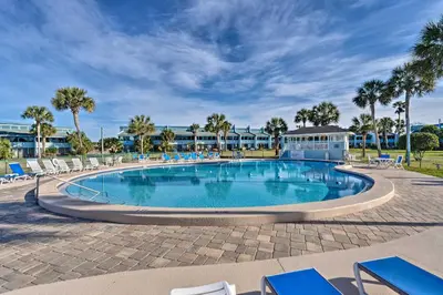 a large swimming pool with blue chairs and palm trees at Pool and Beach Access Sunnyside 55 in PCB! in Panama City